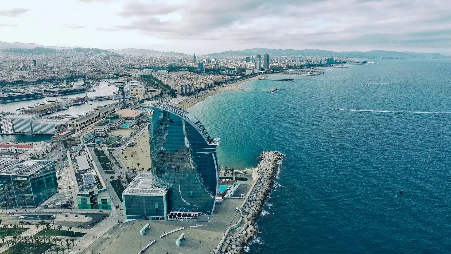 Un bâtiment en verre clair face à la mer sous un ciel gris